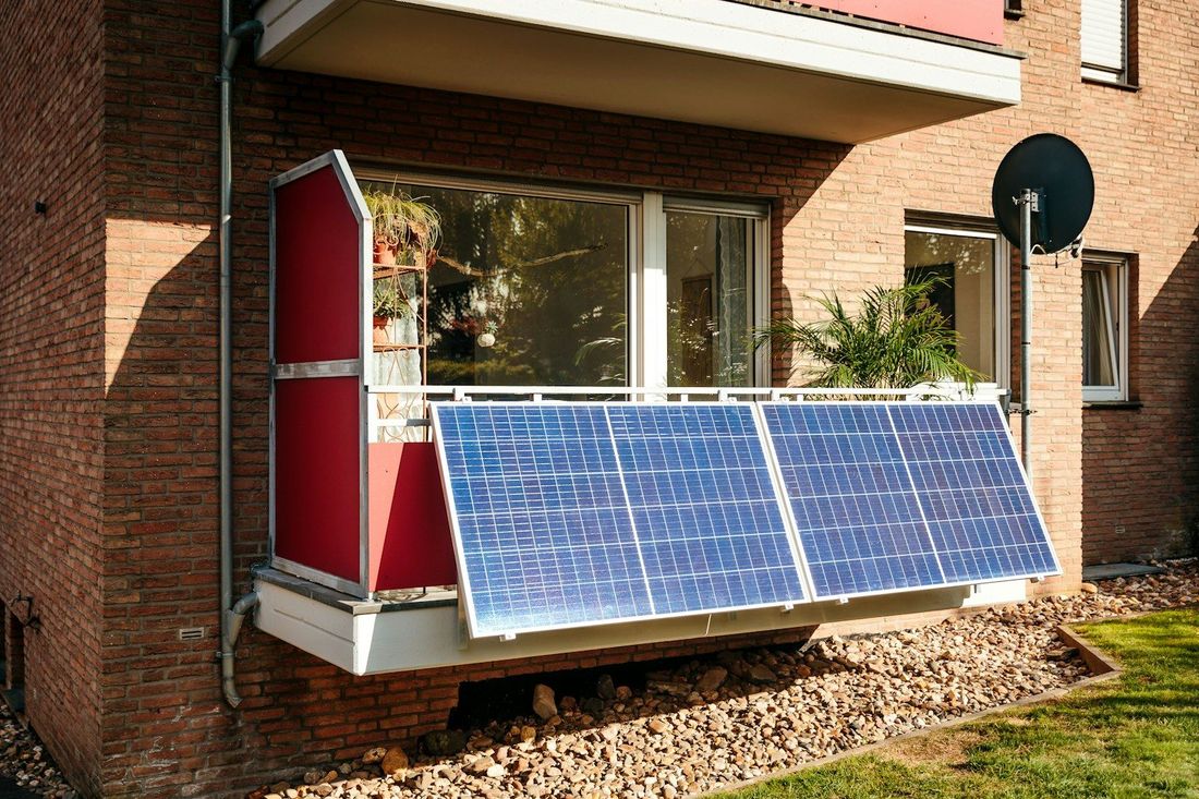 Vier Solarmodule eines Balkonkraftwerks am Geländer eines Balkons befestigt.
