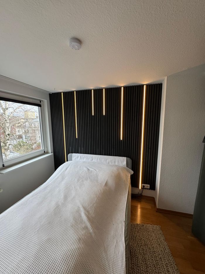 Montierte Akustikpaneele mit integrierten LED-Streifen und Wandsensor zur Steuerung.