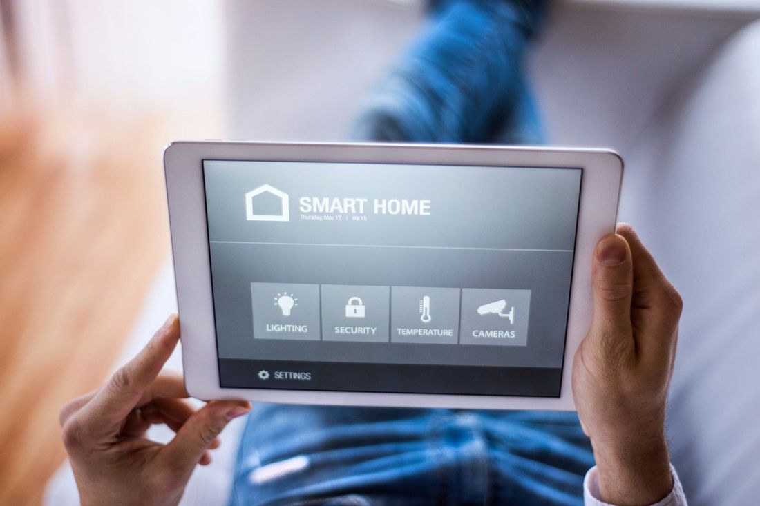 Person bedient auf einem Tablet die Steuerung eines Smart-Home-Systems.
