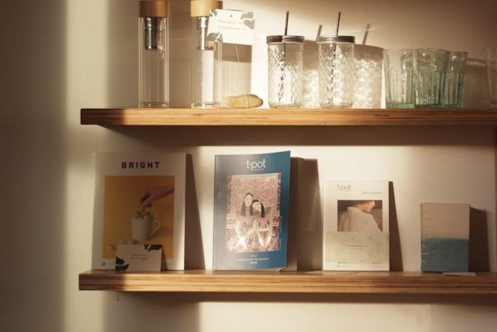 Zwei an der Wand montierte Holzregale mit Gläsern und Büchern.