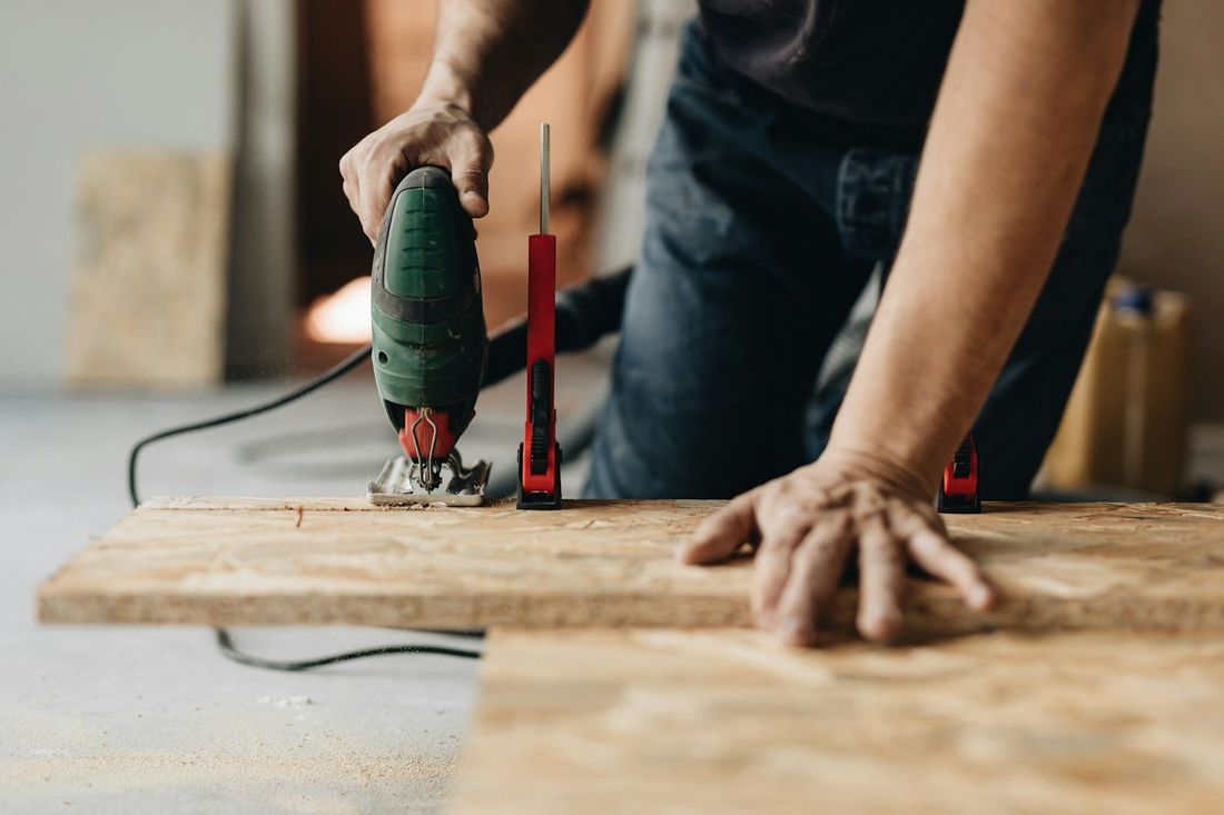 Handwerker sägt mit einer Stichsäge eine Holzplatte zu.